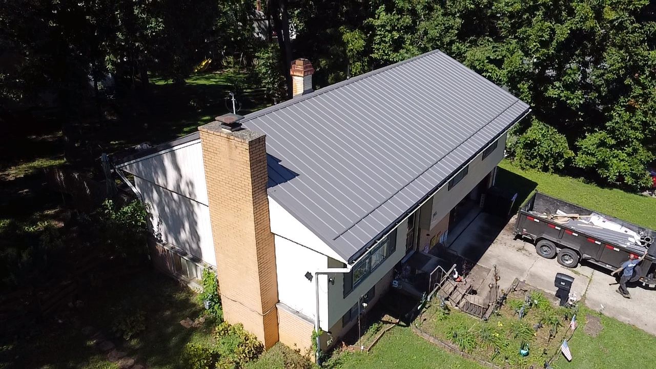 Gray metal roof on a home with brick chimney